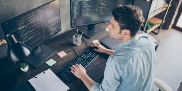 muž u počítače se dvěma monitory